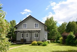 Contemporary Two-story House Of Timber In Countryside In Summer. House Have Nice Landscaping, With Shrubs, Green Lawn And Blooming Trees. Russian Dacha In Moscow Region.
