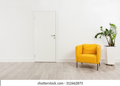 Contemporary waiting room with a yellow armchair and a plant in a white flowerpot behind it