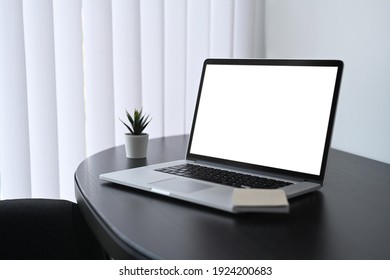 Contemporary workplace with computer laptop, notebook and plant on black wooden table.