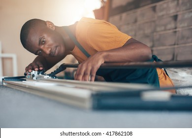 Contemporary young African artisan working with cutting tool 