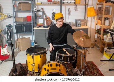 Contemporary Young Drummer In Casualwear Sitting In The Center Of Garage In Front Of Drumset While Going To Train Alone At Leisure