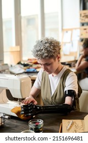 Contemporary Young Woman With Disability Working By Electric Sewing Machine