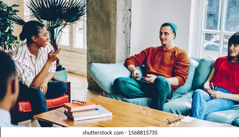 Content African American woman gesturing and pointing while speaking during speech to group of young listeners comfortably placing in soft couch in light room. Meeting in coworking office - Powered by Shutterstock