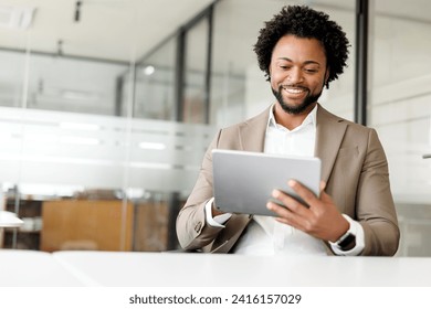 A content African-American businessman uses a tablet in the office, his smile reflecting the successful integration of technology in his workflow, a professional comfortable with digital tools - Powered by Shutterstock