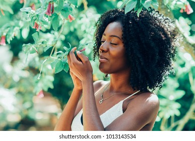 Content Black Woman Smelling Flowers In Park