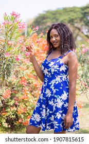 Content Black Woman Smelling Flowers In Park.