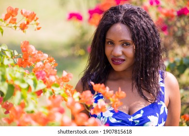 Content Black Woman Smelling Flowers In Park.