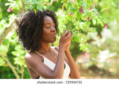 Content Black Woman Smelling Flowers In Park