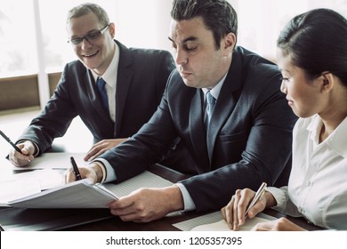 Content business man and woman looking at serious partner signing document. Three business people closing deal. Business meeting and dealing concept