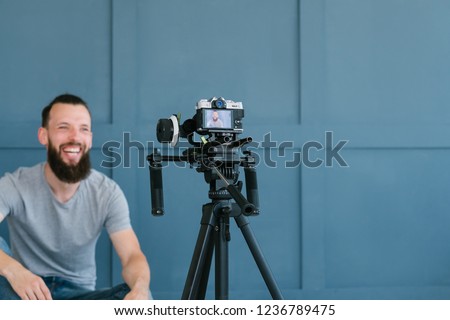 content creation for social media. bearded man shooting video of himself using camera on tripod. modern technology and blogging freelance work concept.