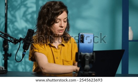 Content creator doing stream, talking to fans about recent news headlines, reading from laptop screen. Woman chatting with subscribers, presenting information on notebook device, camera A