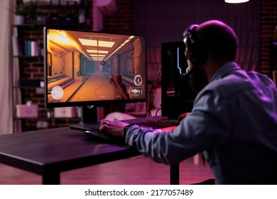 Content creator having fun with video games play competition, using computer to stream online championship. Male gamer playing rpg action tournament game at desk with neon lights.
