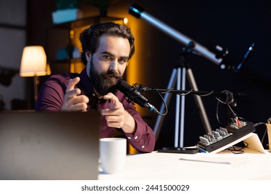 Content creator in home studio doing cool hand gesturing towards camera during live broadcast on online streaming platforms. Entertainer pointing fingers, captivating audience