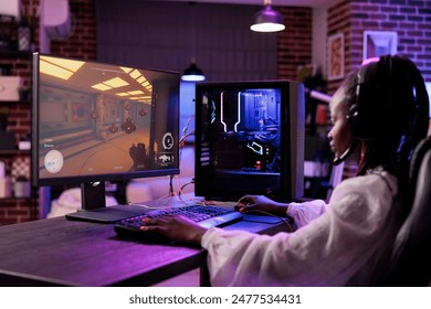 Content creator playing online multiplayer videogame on gaming PC, competing in live esports championship. African american pro gamer streaming game for audience watching from home