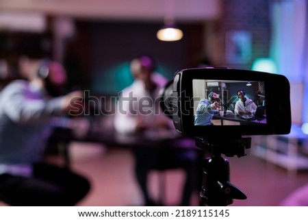 Content creator using camera to record podcast conversation, filming talking show discussion in studio. Social media vlogger chatting and broadcasting live, meeting with happy guest.