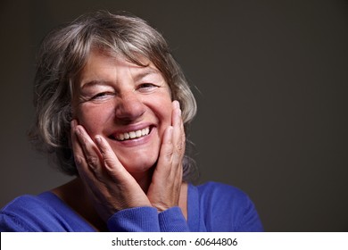 Content Female Senior Citizen Smiling With Hands On Her Face