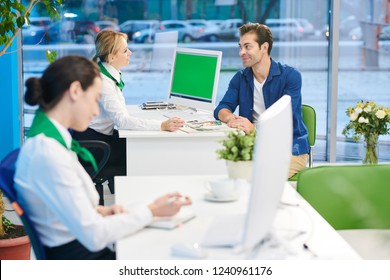 Content Friendly Female Consultant In Corporate Outfit Sitting At Table With Computer And Talking To Handsome Customer While Presenting Bank Service Products