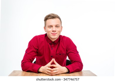 Content Handsome Young Man In Red Shirt Sitting And Smiling Isolated Over White Background