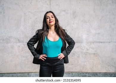 Content Hispanic Female Entrepreneur Standing On Street With Hands On Waist