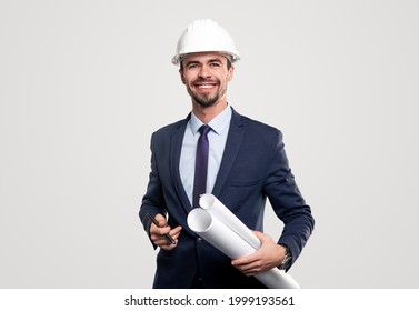 Content male construction architect in formal suit and hardhat with rolled blueprints and pen in hands looking at camera against white background