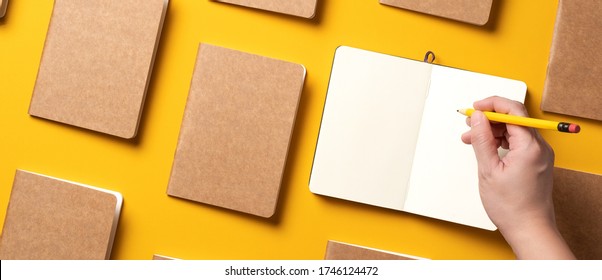 Content Marketing Concept,.top View Of Hand Writing On Open Notebook Align With Kraft Paper Book In Pattern On Yellow Table Background.mockup For Advertise Content Online