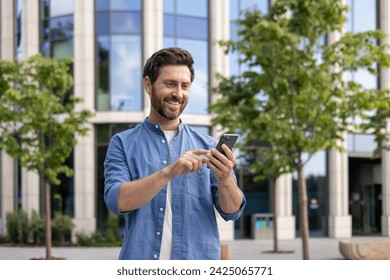 Content middle-aged man with beard engaging with his smartphone, casually dressed, with an office background. - Powered by Shutterstock