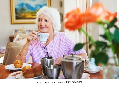 A content old lady enjoying some tea and a muffin