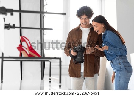 Content photoshoot. Team of photographer man and female smm manager checking the pictures on photocamera while doing photoshoot for elegant shoes