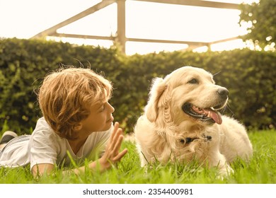 Content preteen boy lying on green meadow with fluffy Golden Retriever dog in summer garden - Powered by Shutterstock