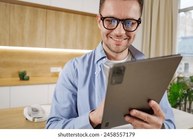 Content professional with glasses using a tablet in a modern, well-lit office setting, exuding a cheerful demeanor.

 - Powered by Shutterstock