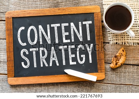 Content Strategy handwritten with white chalk on a blackboard, cup of coffee and biscuit on a wooden background 
