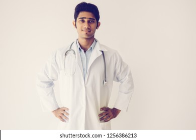 Content Successful General Practitioner In Lab Coat Holding Hands On Hips And Looking At Camera. Serious Confident Handsome Indian Male Doctor Working In Hospital. Healthcare And Medicine Concept