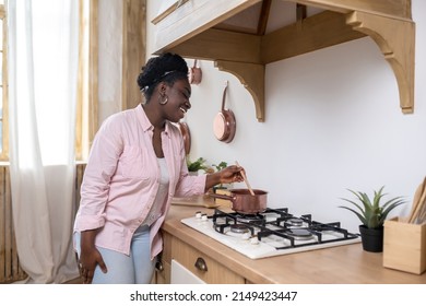 Contented African Woman In Pink Clothes Cooking In The Kitchen