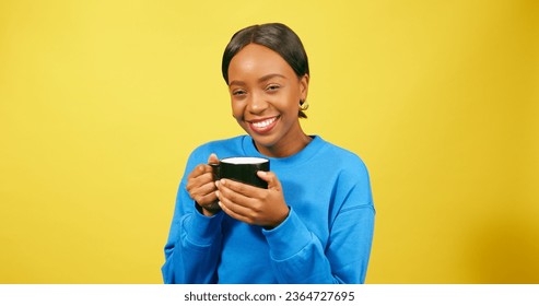 Contented Black woman sips warm drink from mug, yellow studio background - Shutterstock ID 2364727695