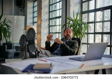 Contented Businessman Relaxing With Legs Up On Desk While Working From Home