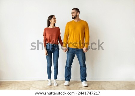 A contented couple stands holding hands, exuding a sense of unity and connection