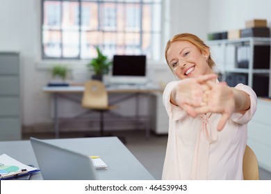 Contented happy young businesswoman stretching her clasped hands in front of her with a lovely smile