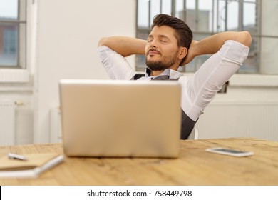 Contented Relaxed Businessman Taking A Quiet Moment Sitting Back In His Chair At The Office With His Hands Clasped Behind His Head And Eyes Closed