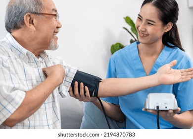 A Contented Retired Man Having A Blood Pressure Check By His Personal Caregiver At His Home With A Smiley Face. Senior Care At Home, Nursing Home For Pensioners.