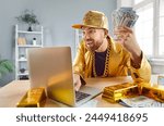 Contented rich man celebrating financial success or win, sitting at a table with gold bars, cash in hand and using a laptop. Convey achievement and prosperity in managing finances online.