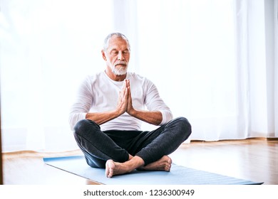 A Contented Senior Man Meditating At Home.