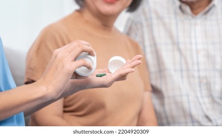 Contented Senior Woman Sit Along Side With Her Husband, Taking Medicines While Her Caregiver Advising Her Medication. Medication For Seniors, Nursing House, Healthcare At Home.