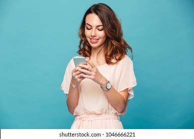 Contented smiling woman typing text message or scrolling through social networks using smartphone isolated over blue background - Powered by Shutterstock