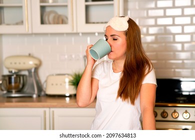 Contented, Sweet Woman Drinking Coffee In Her Kitchen At Home. Cute Female Holding A Mug. Good Morning
