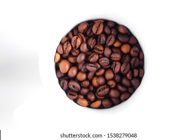 The contents of the cup with coffee, coffee grains in a round white bowl on a white blurred background.