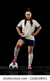 Contestant. Full-length portrait of sportive girl, female soccer player posing isolated on black studio background. Concept of sport, fitness, women in sports. Young sportive wearing football kit.