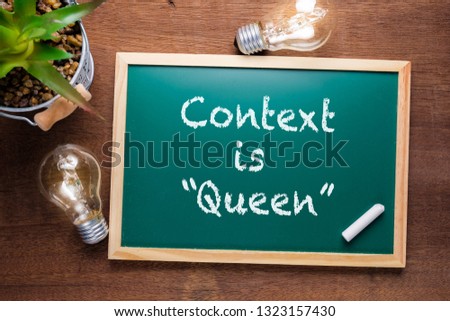 Context is Queen : text on chalkboard with glowing light bulbs on wood table background