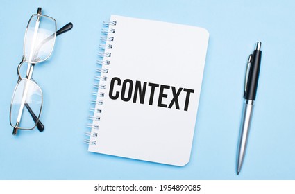 CONTEXT Words In White Notepad, Pen And Glasses On Blue Background. Concept