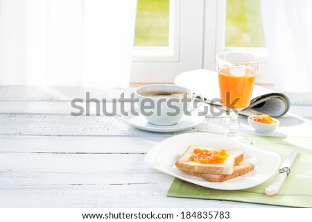 Continental breakfast - coffee, orange juice and toast on white wood table. Background with free text space.