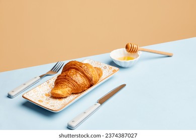 Continental breakfast. Crispy croissant with honey over beige background. Sweet food. Concept of food, bakery, breakfast ideas, taste, freshness. Poser. Copy space for ad